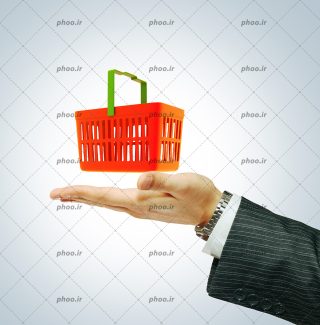 عکس با کیفیت سبد خرید نارنجی با دسته سبز روی دست مرد در پس زمینه خاکستری