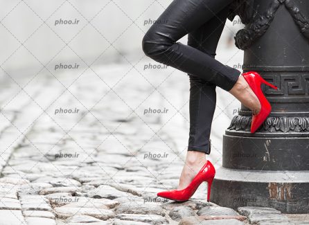عکس با کیفیت زنی با شلوار مشکی و کفش پاشنه بلند قرمز در پیاده رو