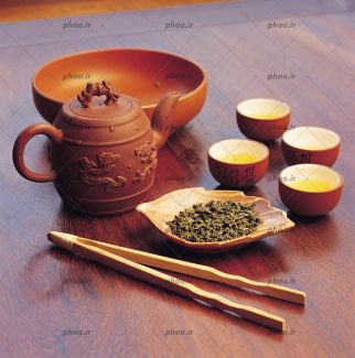 عکس چای خشک سبز داخل ظرف سفالی و فنجان ها و قوری سفالی