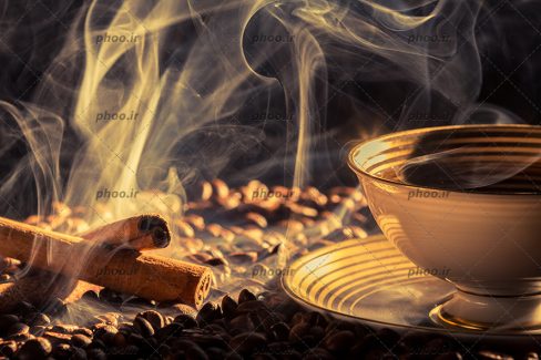 عکس دانه های قهوه و بخار و فنجان سفید