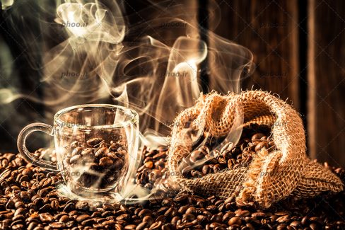 عکس دانه های قهوه در کیسه گونی و لیوان و بخار