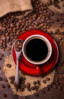 عکس فنجان قرمز قهوه داغ و دانه های قهوه