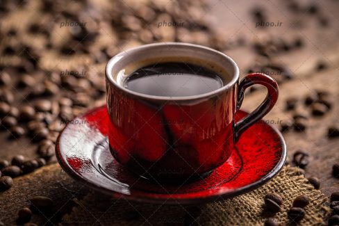 عکس فنجان قرمز قهوه و دانه های قهوه