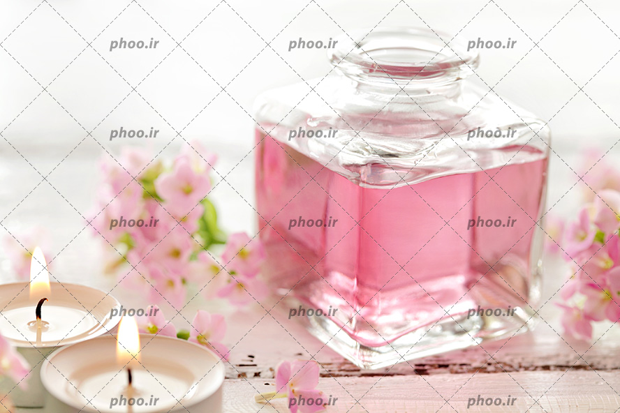 عکس عطر و ادکلن صورتی کنار شمع ها