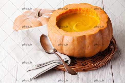 عکس پوره کدو حلوایی داخل کدو تنبل در پس زمینه چوبی