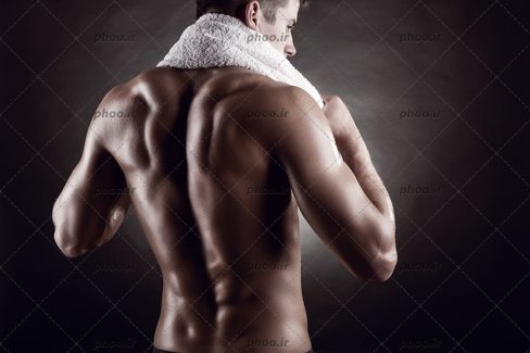 عکس مرد ورزشکار با یک حوله دور گرنش در پس زمینه مشکی