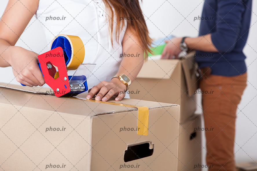 عکس با کیفیت زن در حال بسته بندی جعبه مقوایی با نوار چسب