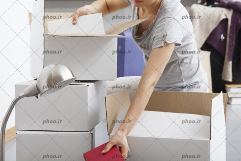 عکس با کیفیت خانم در حال گذاشتن وسایل در جعبه های کارتن در خانه