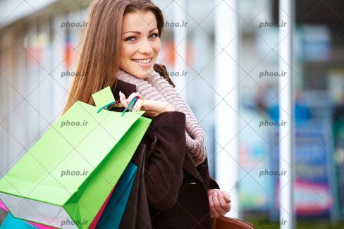 عکس با کیفیت خانمی با لباس گرم و کیسه های خرید در دست در فروشگاه
