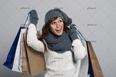 عکس با کیفیت خانم شاد با لباس زمستانه و کیسه های خرید در دست