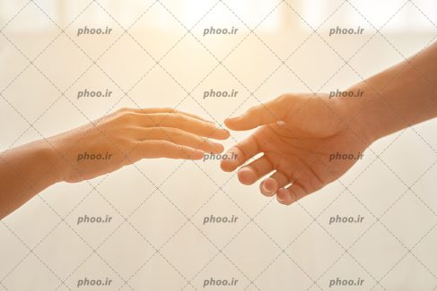 عکس با کیفیت در حال گرفتن دست های یکدیگر و تابیدن نور خورشید در پس زمینه