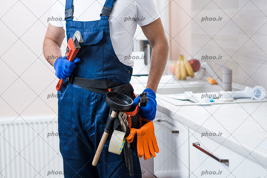 عکس با کیفیت مهندس مکانیک با لباس های مخصوص ایستاده در مقابل کابینت های آشپزخانه