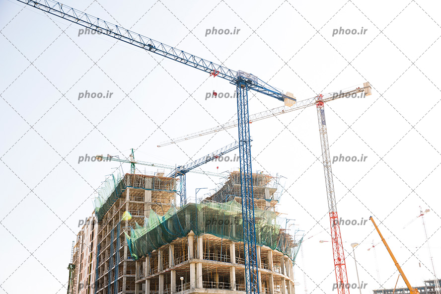 عکس با کیفیت دو تاورکرین در کنار ساختمان های در حال ساخت