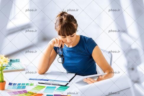 عکس خانم با عینک در دست در حال مطالعه و طراحی