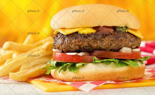 عکس ساندویچ همبرگر و سیب زمینی های سرخ شده روی میز