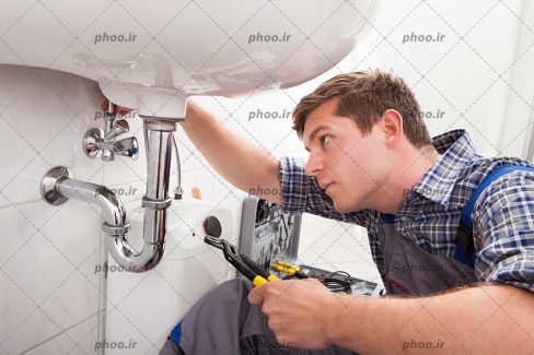 عکس لوله کش در حال لوله کشی با ابزار کار