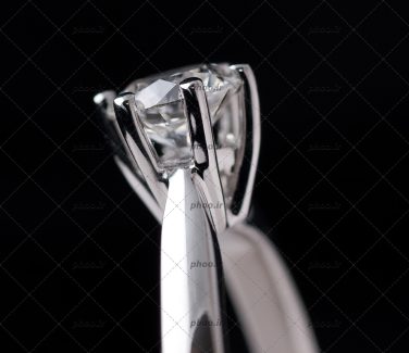 عکس حلقه نقره ای با یک نگین از نمای نزدیک در پس زمینه مشکی