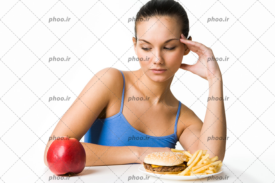 عکس خانم جوان پشت میز و یک ظرف از ساندویچ و سیب زمینی سرخ شده و یک میوه سیب قرمز جلوی او