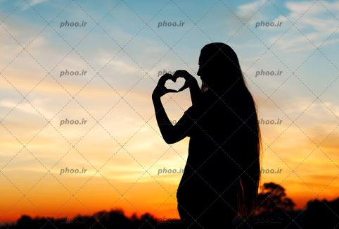 عکس خانم ایستاده در برابر غروب خورشید