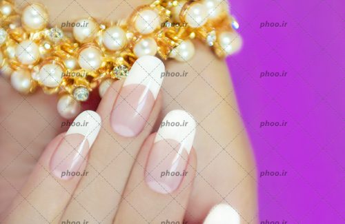 عکس مانیکور کلاسیک در دست زن با زینت در یک پس زمینه بنفش