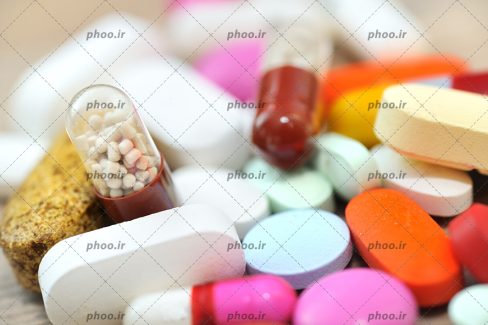عکس قرص ها و کپسول های دارویی رنگی در پس زمینه سفید
