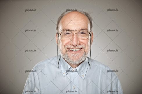 عکس با کیفیت مرد مسن با عینک و لبخند به لب در پس زمینه خاکستری