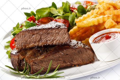 عکس گوشت کباب شده در کنار سیب زمینی سرخ شده و سس و سبزیجات