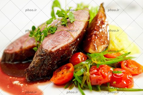 عکس تیکه های گوشت کبابی در کنار گوجه کبابی و پوره سیب زمینی در پس زمینه سفید