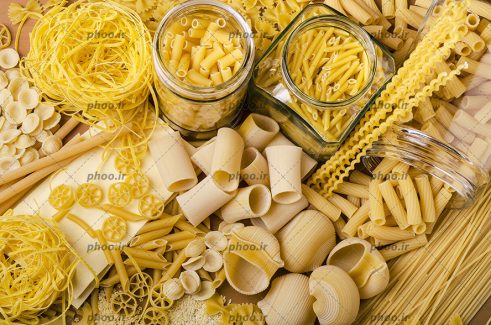 عکس ماکارونی های خام ساده و فرمی بزرگ و کوچک روی زمین و در ظرف های شیشه ای از نمای بالا