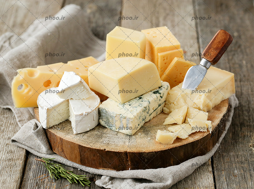 عکس چند نوع پنیر برش خوردی روی تخته چوبی