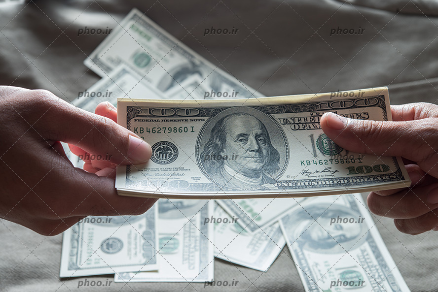 عکس تبادل پول بین دو نفر در پس زمینه پول های روی زمین