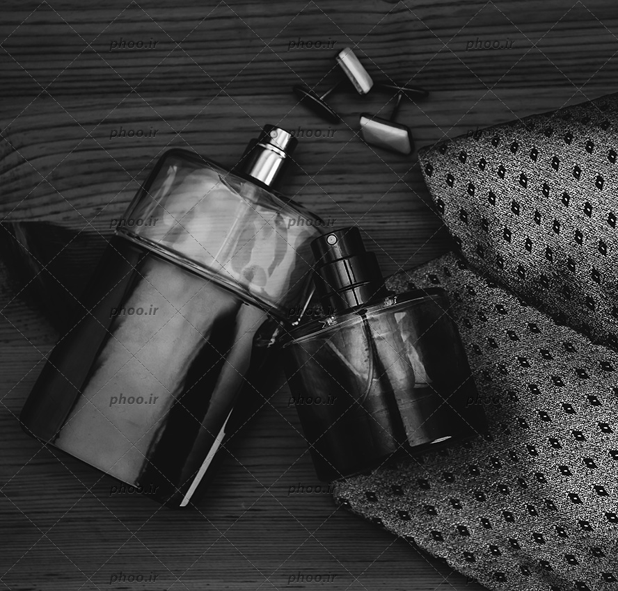 عکس کروات در کنار دکمه سر آستین و ادکلن در پس زمینه مشکی