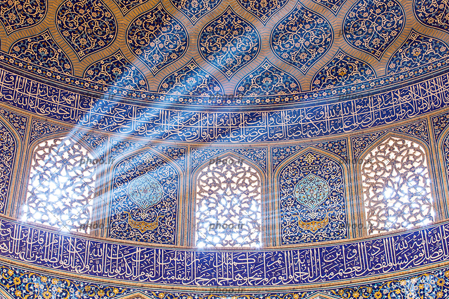 عکس نمای داخلی مسجد با گنبد کاشی کاری شده زیبا با آیات قرآن و پنجره های چوبی که از آن نور به زیبایی در جهت های مختلف به داخل تابیده شده