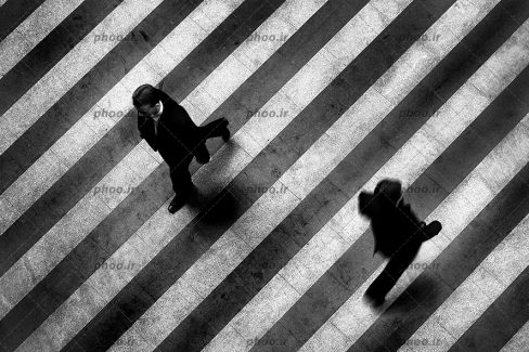 عکس نمای بالا از دو نفر در حال عبور از خط عابر پیاده