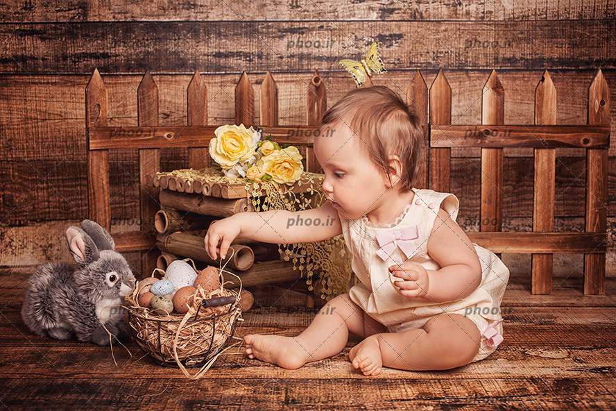 عکس کودک نشسته کنار خرگوش و سبد تخم مرغ با تم مزرعه