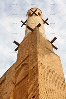 عکس یک مناره آجری بلند در مقابل آسمان ابری