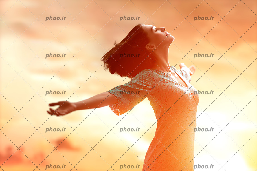 عکس با کیفیت خانم با چشم های بسته و آغوش باز در پس زمینه غروب خورشید