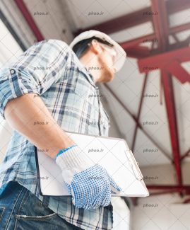 عکس کارگر ساختمان با کلاه و دستکش و طرح در دست