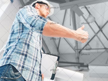 عکس مهندس ساختمان با کلاه ایمنی و نقشه در دست