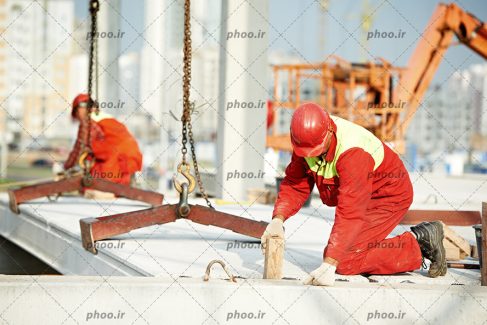 عکس کارگران با لباس کار و کلاه ایمنی در حال انجام کار