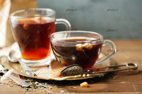 عکس دو فنجان چای گیاهی در پس زمینه چوبی