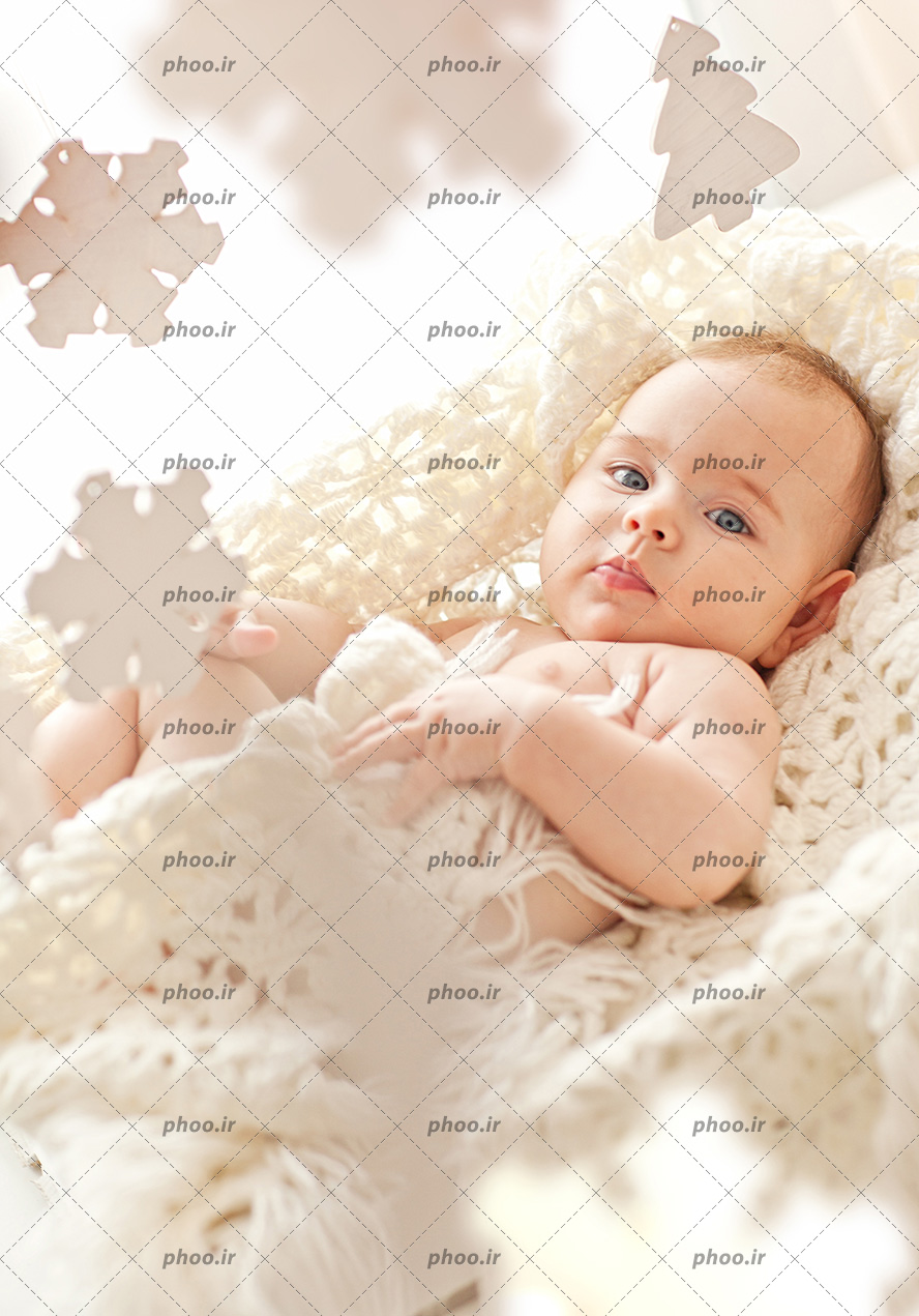 عکس کودک زیبا روی پتو بافتنی در حال نگاه کردن به دوربین