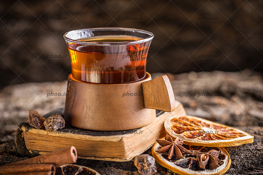 عکس با کیفیت یک فنجان دمنوش در کنار دارچین و میوه خشک