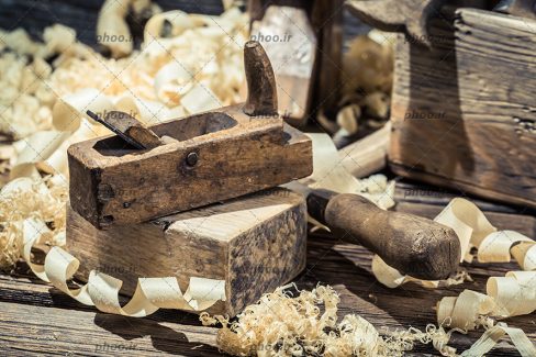 عکس با کیفیت ابزار نجاری و تراشه های چوب روی میز چوبی در کارگاه نجاری