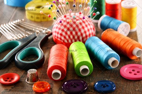 عکس دوک های نخ رنگارنگ چیده شده کنارهم و سوزن