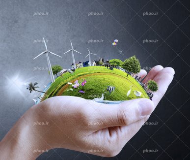 عکس با کیفیت چمن زاری نیم دایره در دستان مرد و در روی آن توربین های بادی در پس زمینه مشکی
