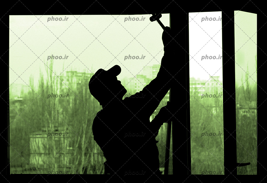 عکس یک کارگر در حال تعمیر پنجره با ابزار در تاریکی