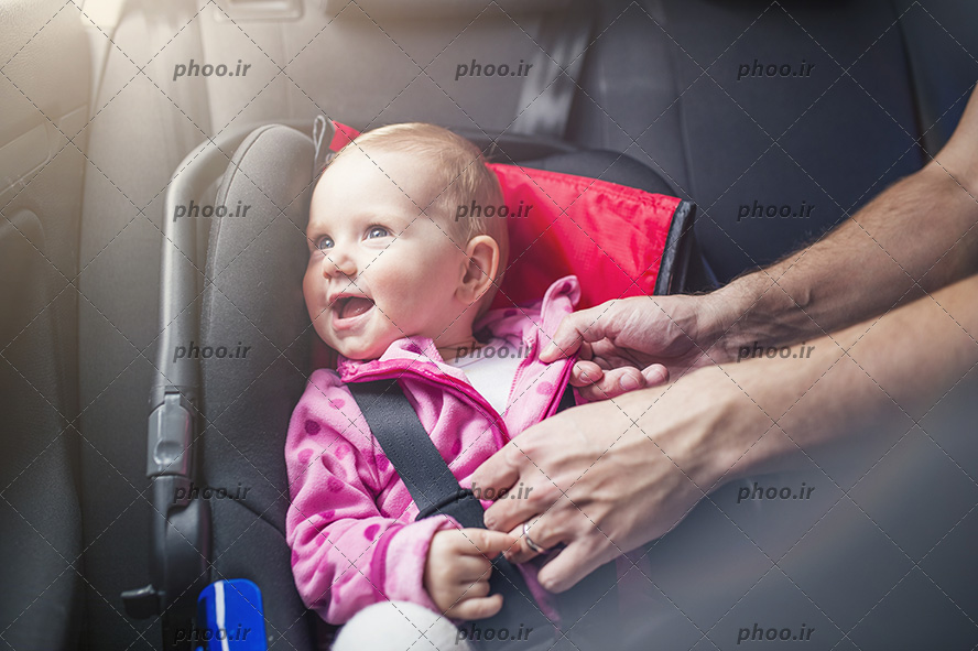 عکس نوزاد روی صندلی کودک با کمربند ایمنی در ماشین