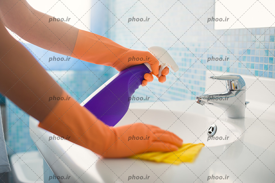 عکس زن در حال تمیز کردن سنگ روشویی و شیر آب با مواد شوینده