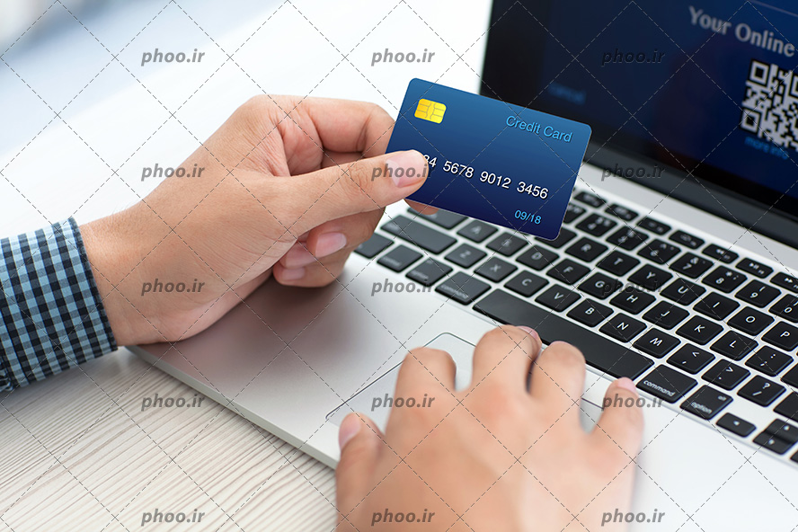 عکس مردی در حال خرید آنلاین با کارت اعتباری در لپ تاپ